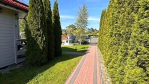 A pathway leading to a building with a red roof, surrounded by neatly trimmed hedges and a well-maintained lawn. - Ferien Bobolin Ferienhäuser by Interhome (Dabki)