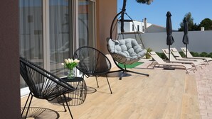 A patio with a hanging chair, two lounge chairs, and a table with flowers. - 3-bedroom villa in gorgeous Zaton with cool AC (Zaton)