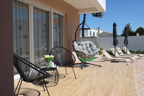 A patio with a hanging chair, two lounge chairs, and a table with flowers. - 3-bedroom villa in gorgeous Zaton with cool AC (Zaton)