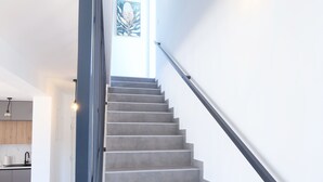 A staircase with a handrail, a light fixture on the wall, and a view of a kitchen area. - 3-bedroom villa in gorgeous Zaton with cool AC (Zaton)