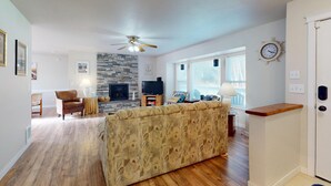 A living room with a sofa, a fireplace, a television, and a stone wall. - Fire Pit, Grill, 3bd, 2ba, Dogs Ok, Fully Fenced Yard (Allee) (Aberdeen)