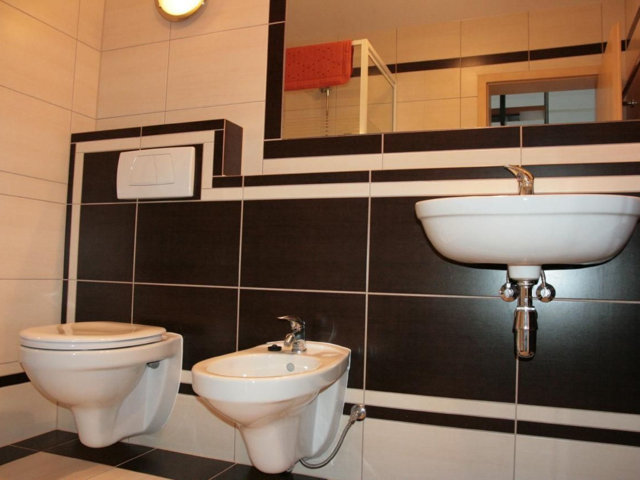 Een badkamer met twee toiletten, een hygiëneschuimer en een wastafel.