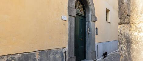 A narrow street with a stone wall, a door, and a small window.