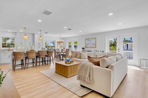 A modern living room with a sofa, coffee table, and dining area with chairs. - Chardonnay Shores - Beautiful 2 Bedroom Home (Anna Maria)