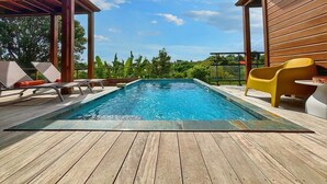 Ett trädäck med en swimmingpool, solstolar och en gul stol.