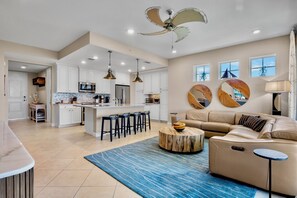 A spacious living area with a large sofa, a coffee table, and a kitchen in the background.