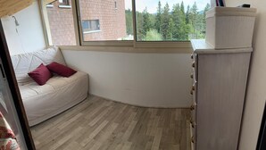 Een hoekzaal met een bank, een raam, een kast en een visgraatvloer.