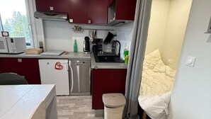 Een kleine keuken met een magnetron, koffiezetapparaat en afwasschuur.