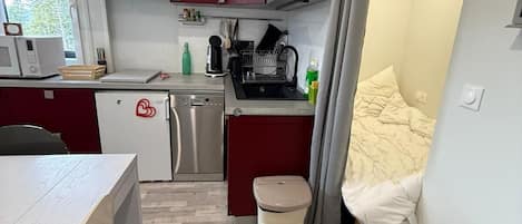 Cocina compacta con microondas, cafetera y escurreplatos.