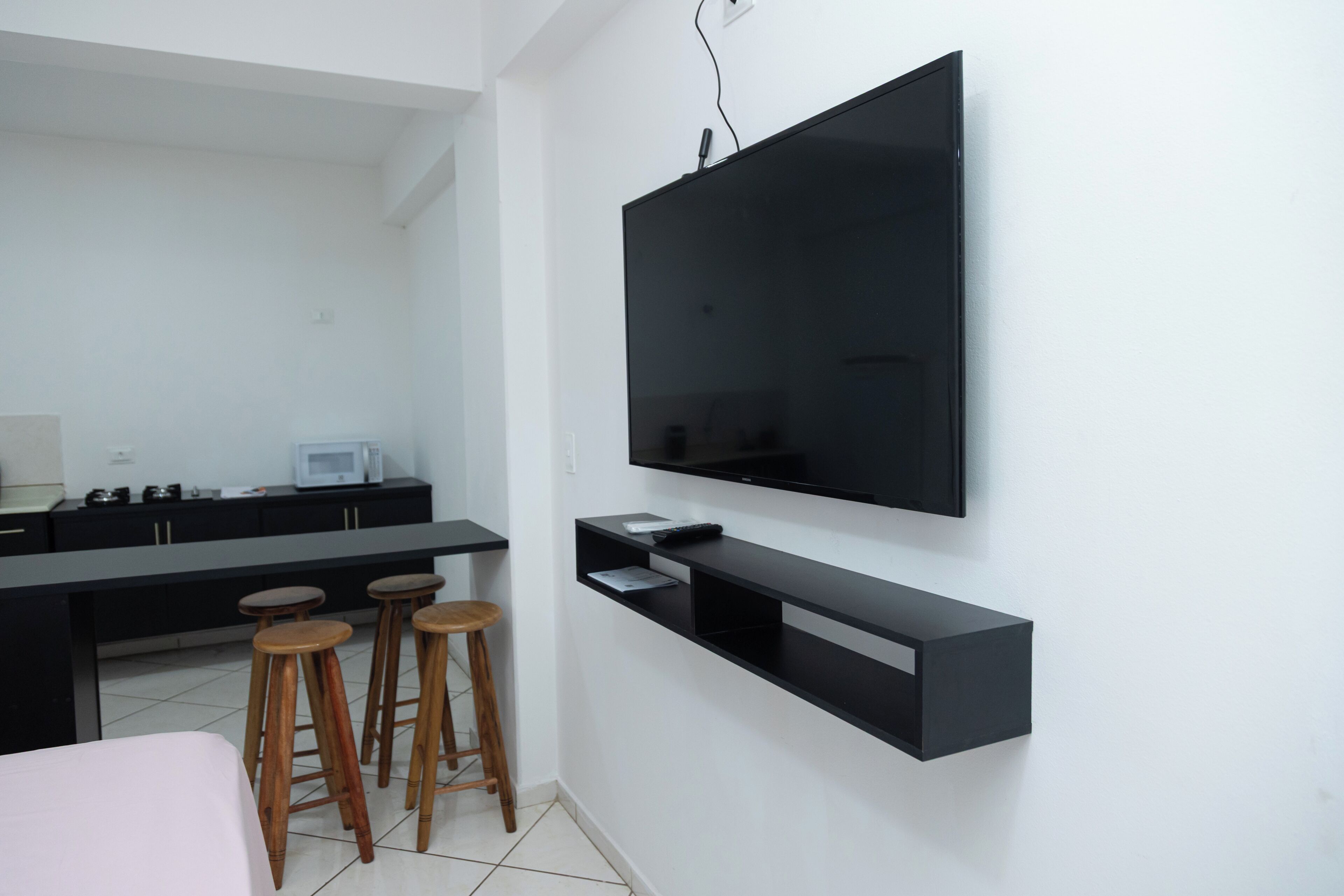 Eine moderne Küche mit Flachbildfernseher, Holzstühlen und einem Essbereich.