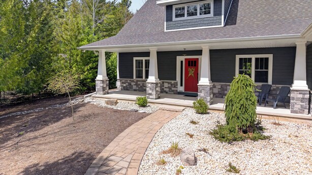 A two-story house with a red door, stone pillars, and a covered porch. - Fish Creek home- near downtown w/ Fire pit (Fish Creek)