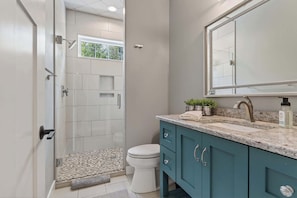A bathroom with a shower, toilet, and vanity with a mirror and sink.