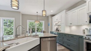 A modern kitchen with a large island, stainless steel appliances, and white cabinetry. - Fish Creek home- near downtown w/ Fire pit (Fish Creek)