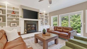 A living room with a fireplace, a sofa, a coffee table, and a television. - Fish Creek home- near downtown w/ Fire pit (Fish Creek)