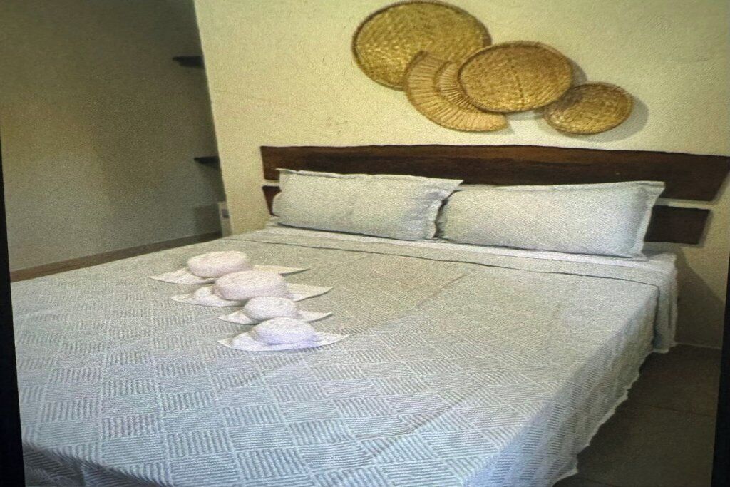 Una cama con una colcha estampada, dos almohadas y una pared decorada con cestas tejidas.