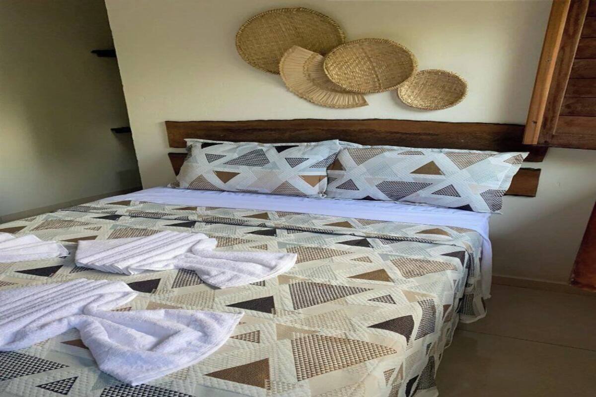 Ein Bett mit einem geometrisch gemusterten Überwurf, einem Holzkopfende und einer Wand mit gewebten Körben.