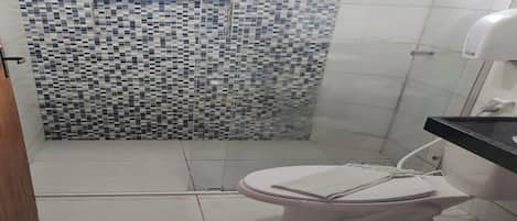 Une salle de bain avec une douche carrelée, des toilettes et un lavabo.