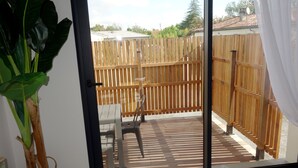 A room with a sliding glass door leading to an outdoor patio with a wooden fence, a chair, and a potted plant.