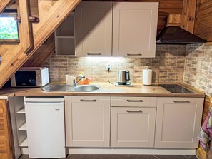 Uma cozinha compacta com máquina de lavar louça embutida, chaleira e micro-ondas.