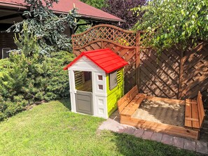 A small playhouse with a red roof and a wooden playpen attached. - Willa Kinga z kominkiem by Interhome (Rewal)