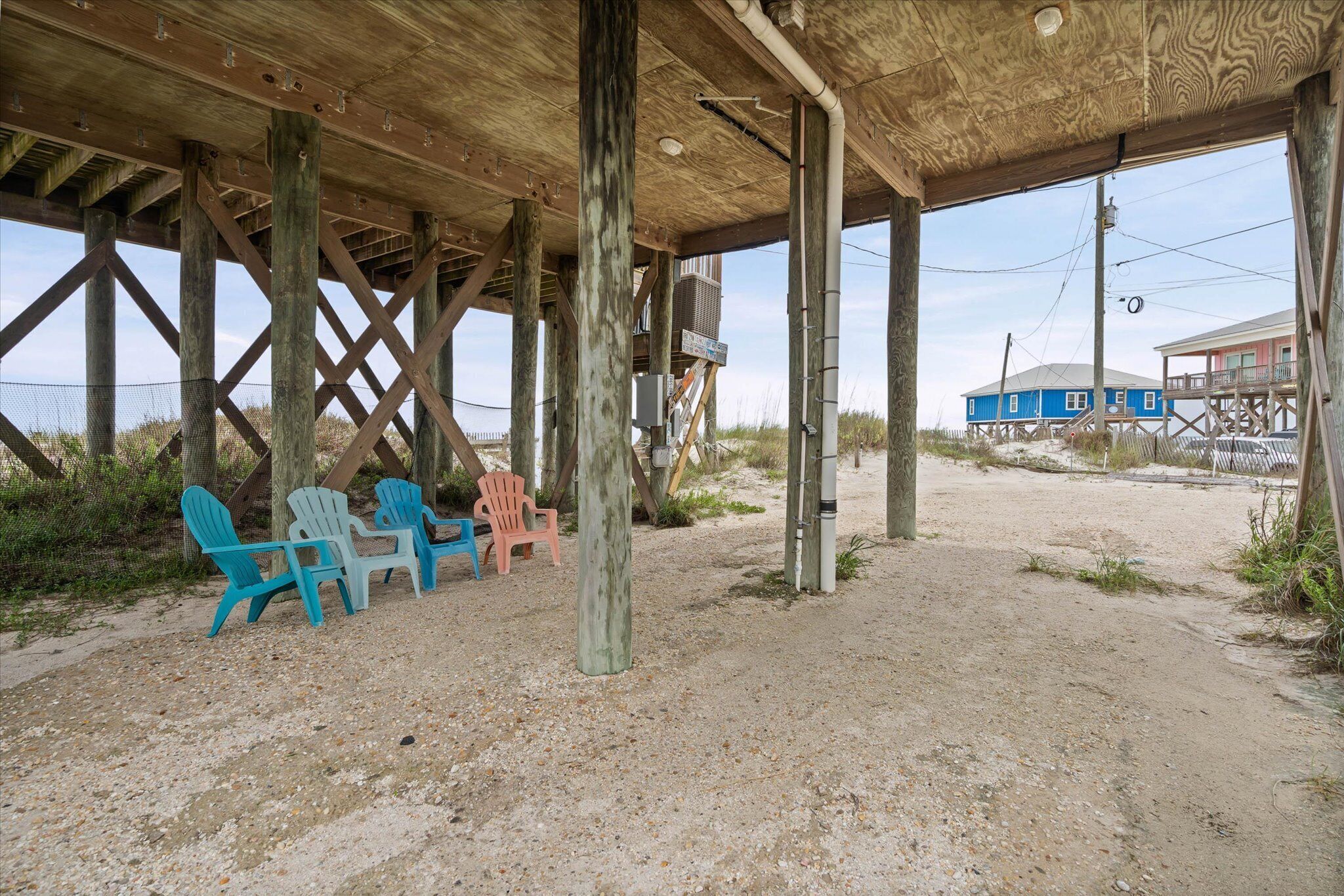 Eine Strandhütte aus Holz mit Stühlen und Sandboden.