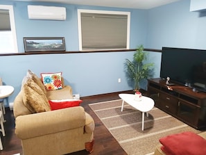 A living room with a sofa, a coffee table, a TV, and a plant.