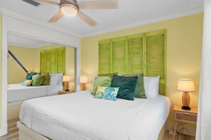 Ein Hotelzimmer mit einem Bett, zwei Nachttischen, einem Deckenventilator und einem Spiegel.