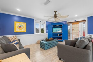Ein Wohnzimmer mit blauer Akzentwand, Deckenventilator, Fernseher und blauem Unterhaltungsschrank.