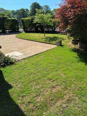 A well-maintained lawn with a paved area, surrounded by trees and shrubs. - Loggia house for 4 people (Carolles)