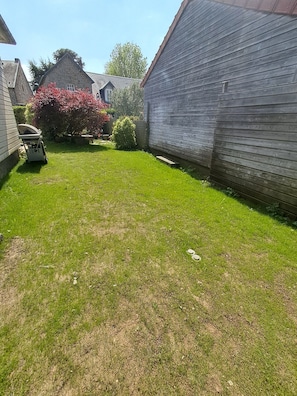 Ein Garten mit Rasen, Holzpforte und Steinmauer.
