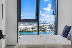 A bedroom with a large window, a bed, and a view of a cityscape and water. - Luxury 2-Bedroom Apartment in Downtown Miami with AC (Miami)
