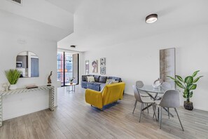 A modern living room with a yellow sofa, a glass dining table, and a gray couch. - Luxury 2-Bedroom Apartment in Downtown Miami with AC (Miami)