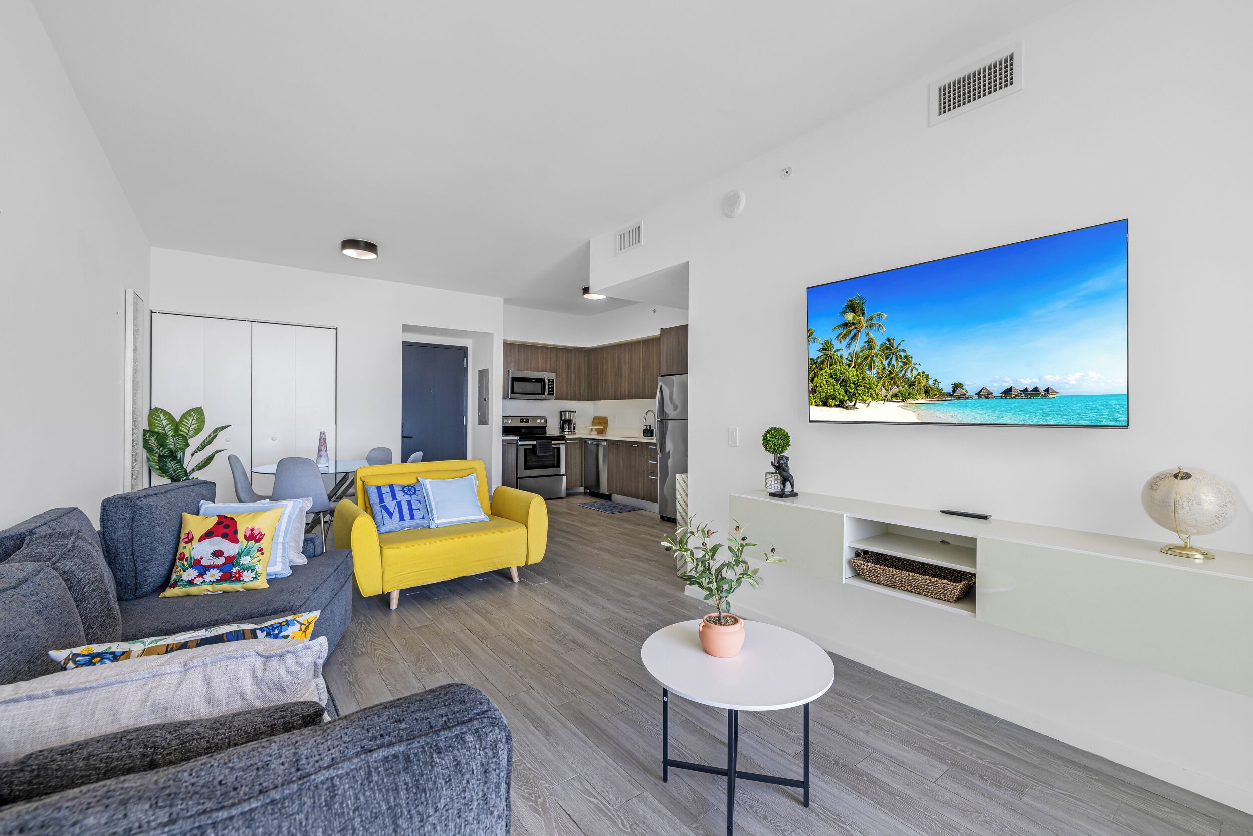 A modern living room with a sofa, armchair, and a small table with a plant.