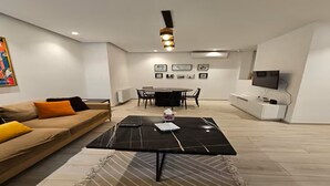 Un salon moderne comprenant un canapé, une table basse, une table à manger, des chaises et un téléviseur à écran plat.
