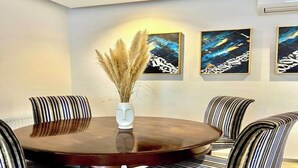 Un espace repas avec une table ronde, des chaises à motifs rayés et des œuvres d’art abstraites accrochées au mur.