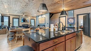 Une cuisine spacieuse dotée d’un grand îlot central, d’un plafond en bois et d’appareils électroménagers modernes.