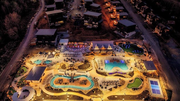 Vue aérienne d’un complexe hôtelier doté de plusieurs piscines, d’une vaste place centrale et de nombreux bâtiments.