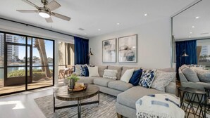 Uma sala de estar moderna com um sofá grande, uma mesa de centro e vista para o exterior.