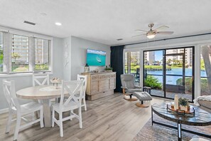 A modern living room with a dining area, a TV, and a view of a pool. - ☀️Steps to the Beach | 5 Pools | Seascape Boardwalk Villa 175☀️ (Miramar Beach)