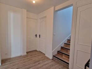 A hallway with white doors, wooden flooring, and a staircase with wooden steps. - "Chez G & G" Renovated family home sleeps 8, walking distance to beach. (La Hague)