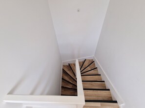 A staircase with wooden steps and white walls. - "Chez G & G" Renovated family home sleeps 8, walking distance to beach. (La Hague)