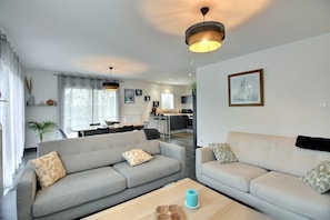 Ein modernes Wohnzimmer mit zwei Sofas, einem Couchtisch und einem Essbereich im Hintergrund.