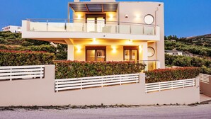 Ein modernes, zweistöckiges Haus mit Balkon, umgeben von angelegten Gärten.