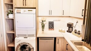 Eine kleine Küche mit Waschmaschine, Kaffeemaschine und einer Tafel mit einer Willkommensbotschaft.