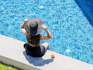 A person sitting by a swimming pool with a drink on the edge. - Villa Lamon by Interhome (Agios Vasilios)