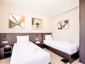 Una habitación de hotel con dos camas, una mesita de noche con lámpara y una obra de arte en la pared.