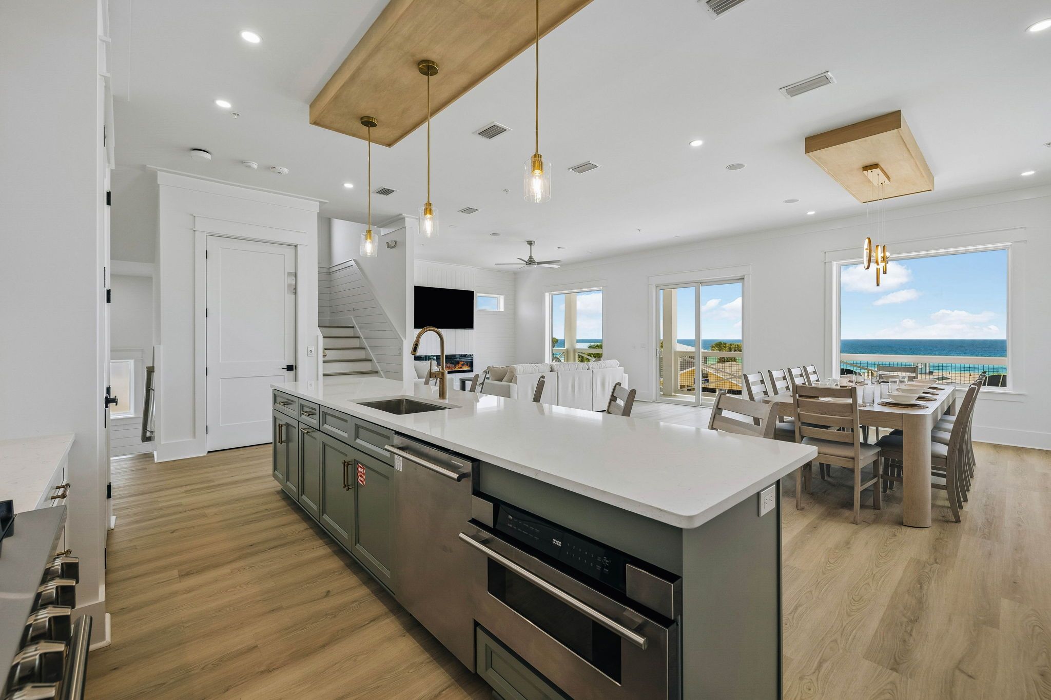 A modern kitchen with a large island, stainless steel appliances, and a view of the ocean.