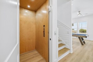 A modern interior with a wooden door, a staircase, and a pool table. - Brand New • Gulf Views, Private Pool, Game Room, & Elevator • Steps to Beach (Panama City Beach)