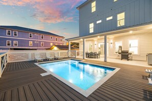 A pool area with a wooden deck, lounge chairs, and a barbecue grill. - Brand New • Gulf Views, Private Pool, Game Room, & Elevator • Steps to Beach (Panama City Beach)