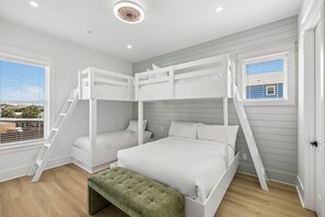 A bunk bed room with a green bench, white bedding, and a view through the window. - Brand New • Gulf Views, Private Pool, Game Room, & Elevator • Steps to Beach (Panama City Beach)